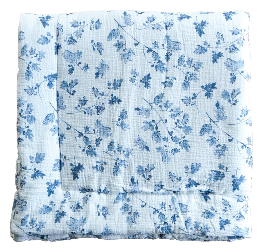Muslin swaddle blanket in Fig, folded, with indigo fig leaves and branches painted on white cloth